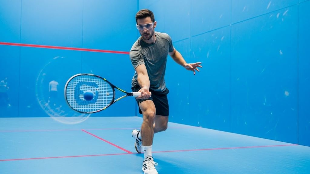 Racquetball player mid-swing demonstrating proper form with safety goggles