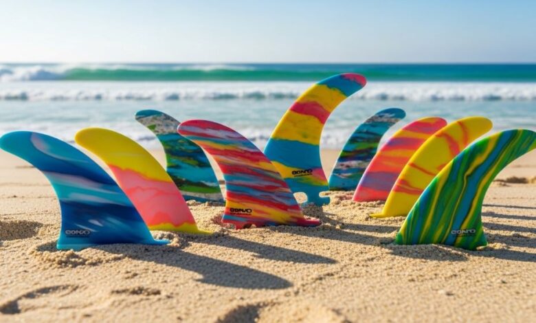 Colorful recycled plastic surfboard fins displayed on sandy beach with ocean waves in background