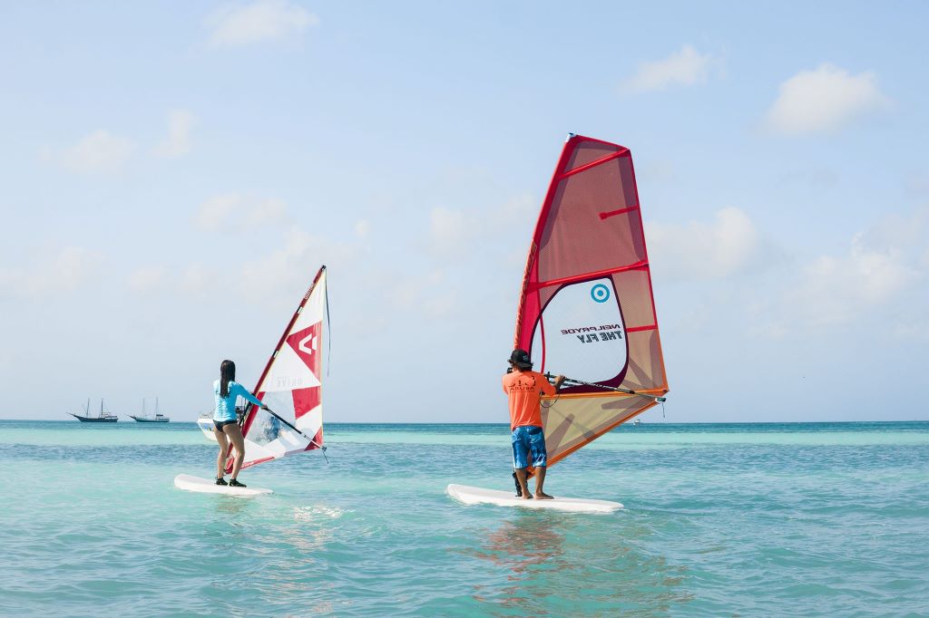 Beginner learning windsurfing on the clear blue waters of Aruba