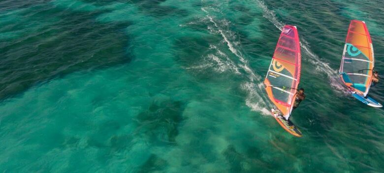 Instructor teaching a tourist basic windsurfing techniques on Aruba beach