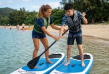 Beginner kneeling calmly on a stable paddleboard on a calm lake.